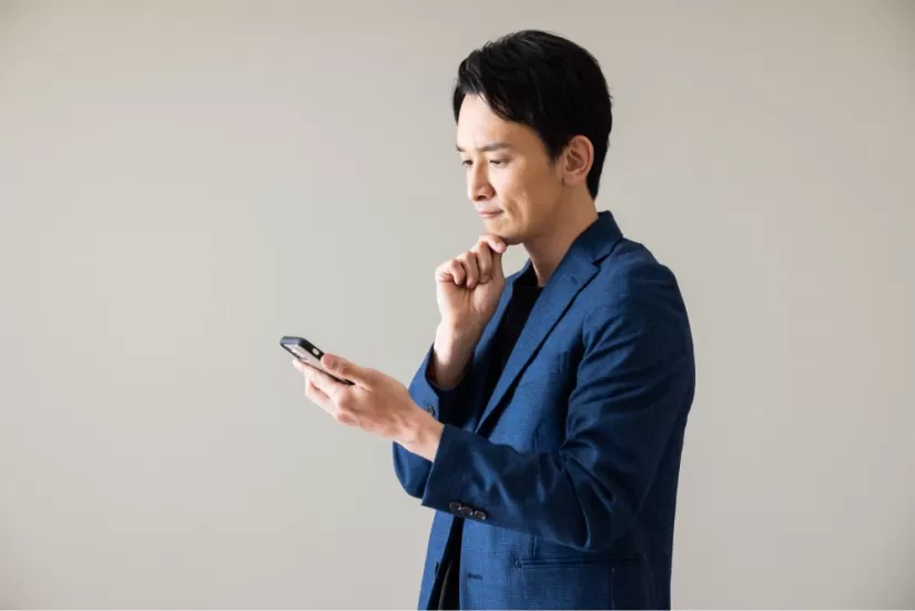 スマホを見ながら考える男性